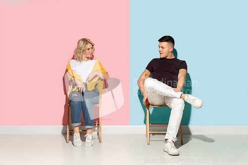 Image of Young emotional man and woman on pink and blue background