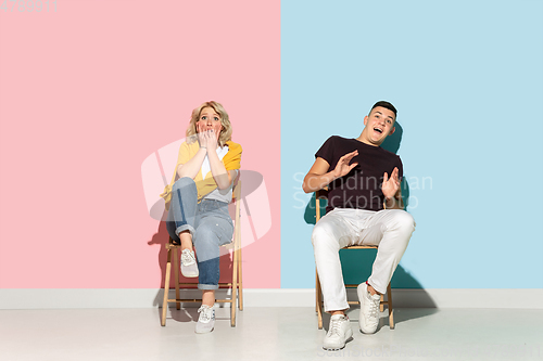 Image of Young emotional man and woman on pink and blue background