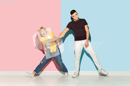 Image of Young emotional man and woman on pink and blue background
