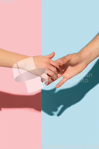 Image of Female and male hands holding on pink and blue background