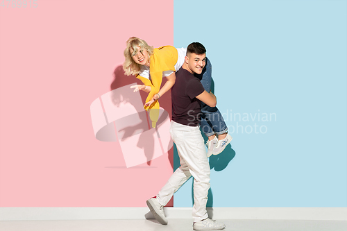 Image of Young emotional man and woman on pink and blue background