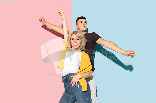 Image of Young emotional man and woman on pink and blue background