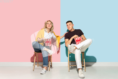 Image of Young emotional man and woman on pink and blue background