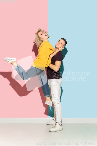 Image of Young emotional man and woman on pink and blue background