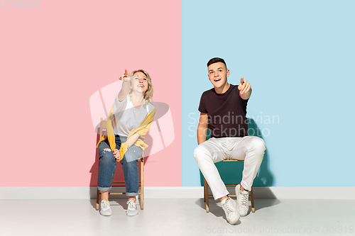 Image of Young emotional man and woman on pink and blue background