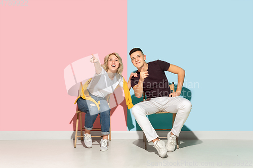 Image of Young emotional man and woman on pink and blue background