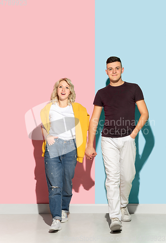 Image of Young emotional man and woman on pink and blue background