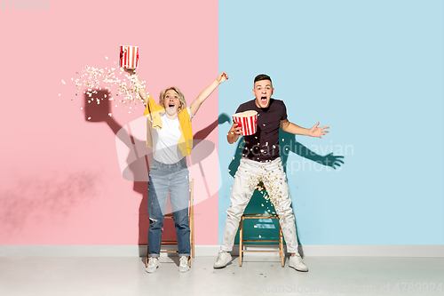 Image of Young emotional man and woman on pink and blue background