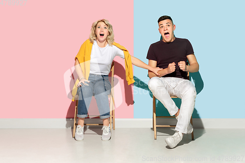 Image of Young emotional man and woman on pink and blue background