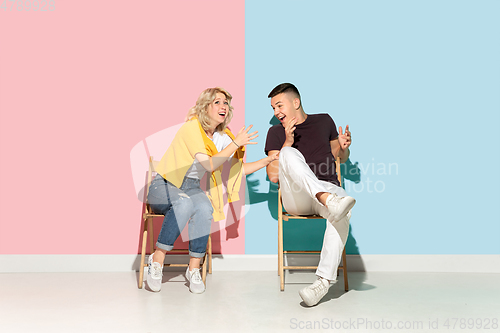 Image of Young emotional man and woman on pink and blue background