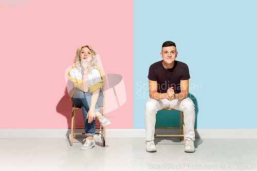 Image of Young emotional man and woman on pink and blue background