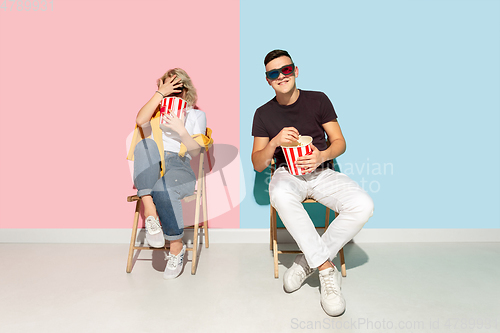 Image of Young emotional man and woman on pink and blue background