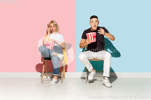 Image of Young emotional man and woman on pink and blue background