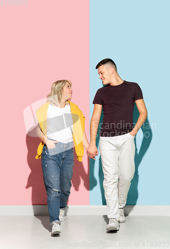 Image of Young emotional man and woman on pink and blue background