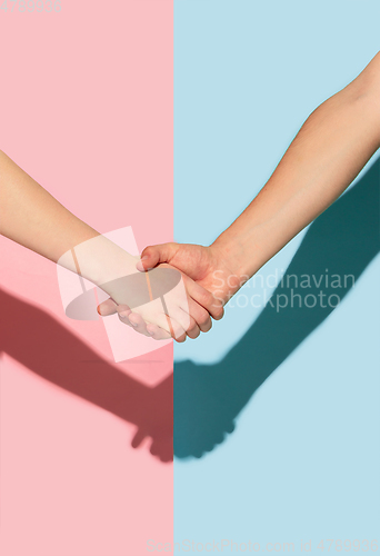 Image of Female and male hands holding on pink and blue background