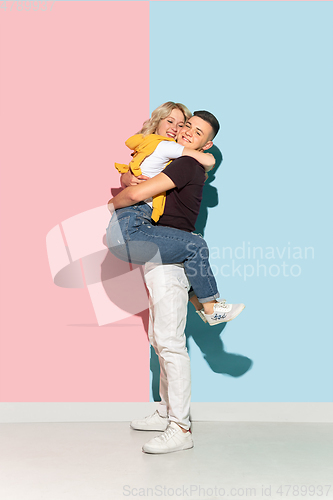 Image of Young emotional man and woman on pink and blue background