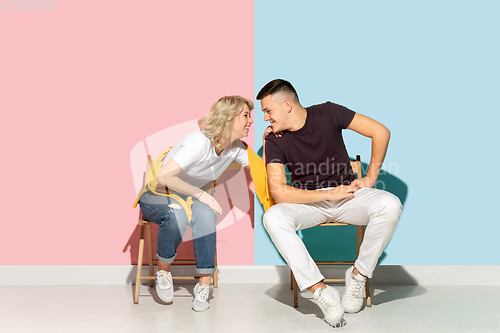 Image of Young emotional man and woman on pink and blue background