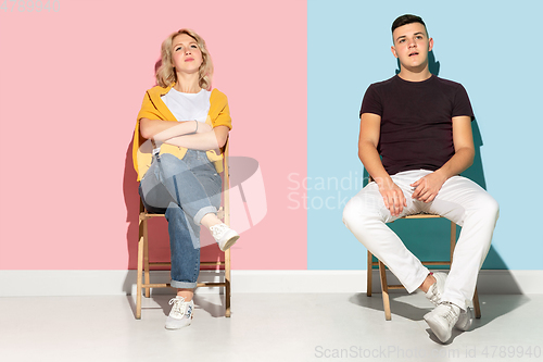 Image of Young emotional man and woman on pink and blue background