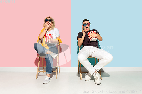 Image of Young emotional man and woman on pink and blue background