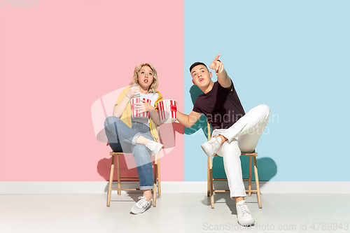 Image of Young emotional man and woman on pink and blue background