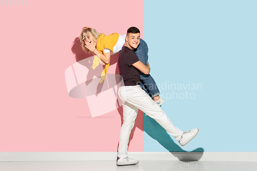 Image of Young emotional man and woman on pink and blue background