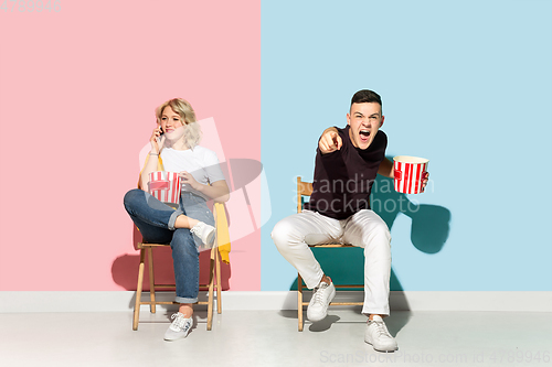 Image of Young emotional man and woman on pink and blue background