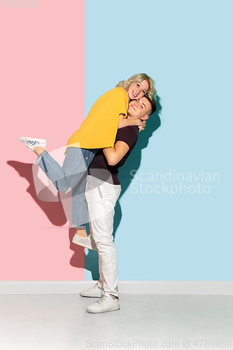 Image of Young emotional man and woman on pink and blue background