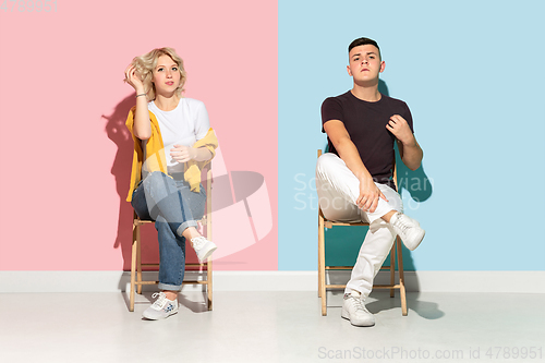 Image of Young emotional man and woman on pink and blue background