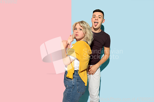 Image of Young emotional man and woman on pink and blue background