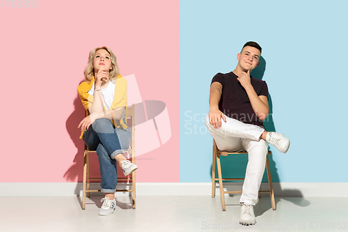 Image of Young emotional man and woman on pink and blue background