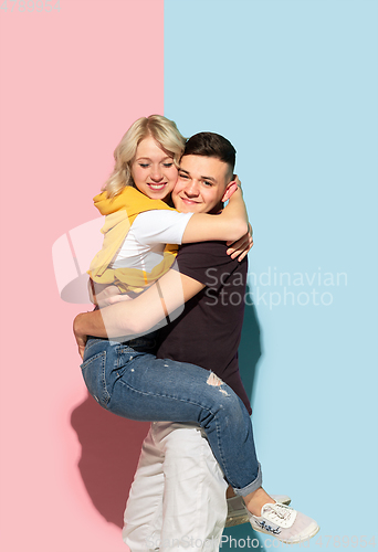 Image of Young emotional man and woman on pink and blue background