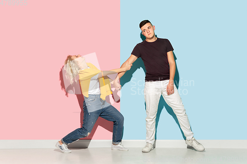 Image of Young emotional man and woman on pink and blue background