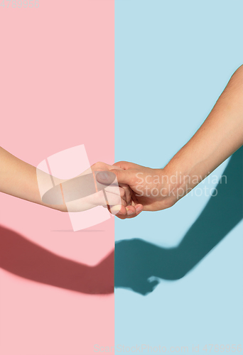 Image of Female and male hands holding on pink and blue background