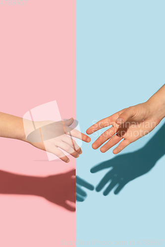 Image of Female and male hands holding on pink and blue background