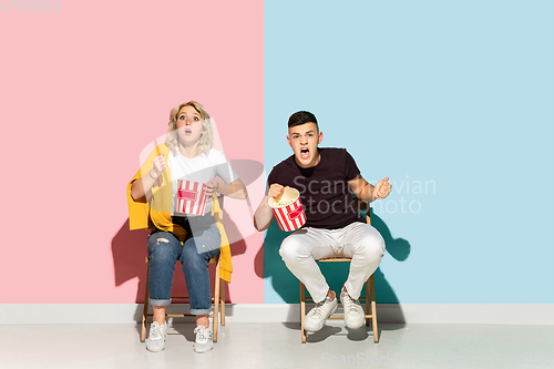 Image of Young emotional man and woman on pink and blue background