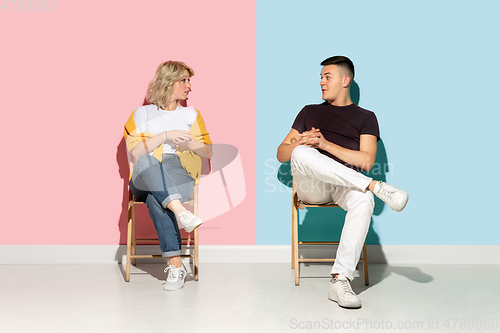 Image of Young emotional man and woman on pink and blue background