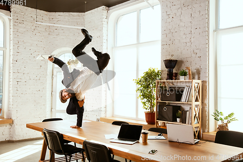 Image of Businessman having fun dancing break dance in the office at work