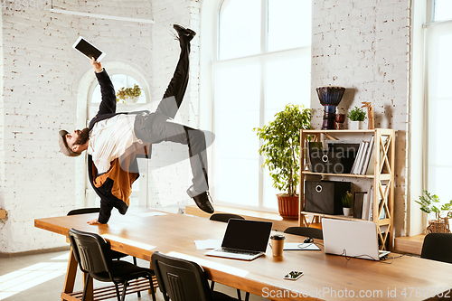 Image of Businessman having fun dancing break dance in the office at work