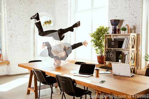 Image of Businessman having fun dancing break dance in the office at work