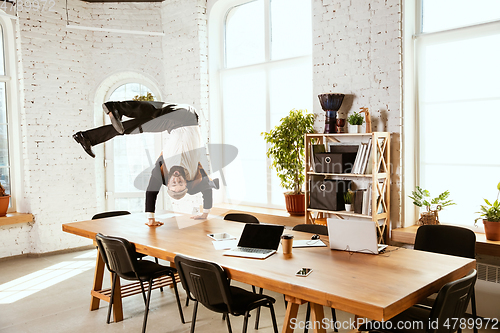 Image of Businessman having fun dancing break dance in the office at work