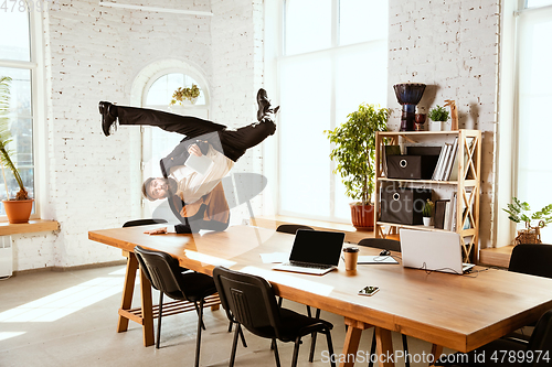 Image of Businessman having fun dancing break dance in the office at work