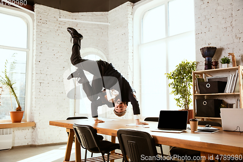 Image of Businessman having fun dancing break dance in the office at work