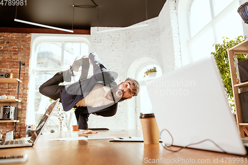 Image of Businessman having fun dancing break dance in the office at work