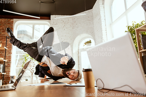 Image of Businessman having fun dancing break dance in the office at work