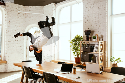 Image of Businessman having fun dancing break dance in the office at work