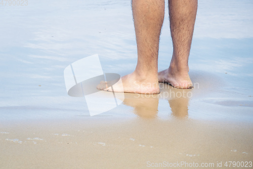 Image of male bare feet in the wet sand