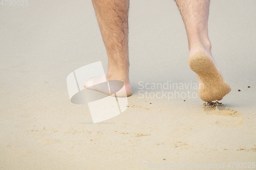 Image of male bare feet in the wet sand