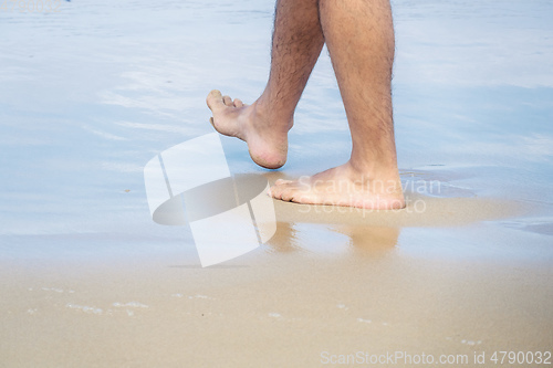 Image of male bare feet in the wet sand