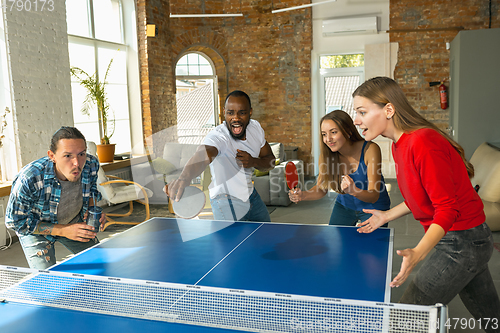 Image of Young people playing table tennis in workplace, having fun