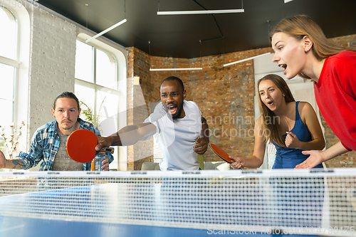 Image of Young people playing table tennis in workplace, having fun